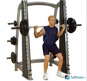 An athlete works out on a Smith machine