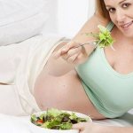 Беременная девушка ест салат