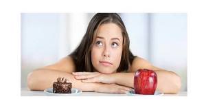 The girl is thinking about eating a cake or an apple