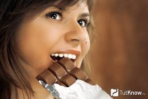 Девушка кусает шоколадную плитку