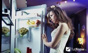 A girl with a sad face examines the contents of the refrigerator