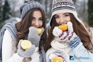 Девушки на улице зимой едят фрукты