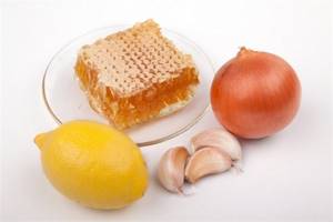Photo of honey in a comb, garlic, onion and lemon