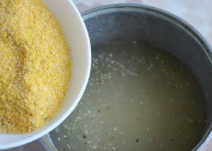 corn flour is poured into a cauldron with water