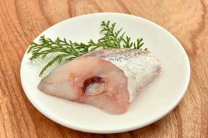 piece of fresh pollock with herbs on a white plate