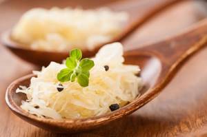 sauerkraut with black peppercorns and herbs in a spoon