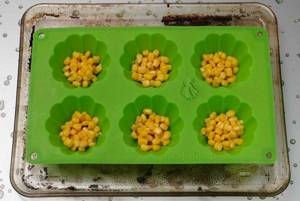 Place olives and corn on the bottom of the pans.