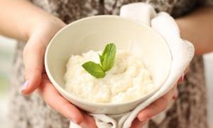 Rice porridge with milk in the hands of a girl