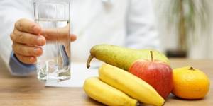 Стакан воды в руке у человека и фрукты на столе