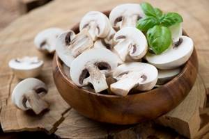 fresh champignons, cut into slices, in a bowl on a stump