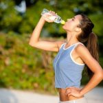 woman drinks water while jogging