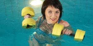 Woman with dumbbells in the pool